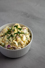 Homemade Healthy Potato Salad with Eggs in a Bowl on a gray background, side view.
