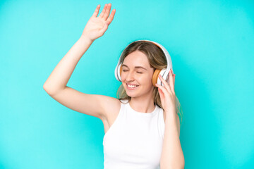 Blonde English young girl isolated on blue background listening music and dancing