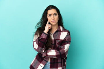 Young caucasian woman isolated on blue background having doubts and thinking