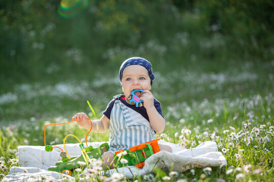 Cute baby is sitting on a linen blanket and playing with colored educational toys. Products for children.