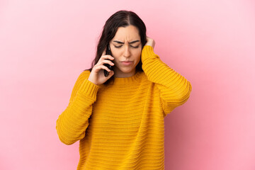 Young caucasian woman using mobile phone isolated on pink background frustrated and covering ears