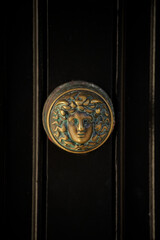 Vertical shot of an old door knob with female head design on Georgian black front door