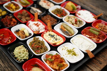 Turkish and Greek appetizers (meze) table. Traditional Turkish cuisine cold appetizers. Different types of appetizers in colorful special plates. Olives, hummus, yogurt, pickles etc.Selective focus.