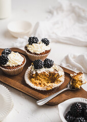 muffin cupcake paper mold carrot cake topped with whipped cream and berries 
blackberry