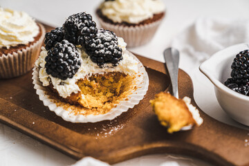muffin cupcake paper mold carrot cake topped with whipped cream and berries 
blackberry
