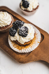 muffin cupcake paper mold carrot cake topped with whipped cream and berries 
blackberry