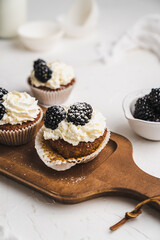 muffin cupcake paper mold carrot cake topped with whipped cream and berries 
blackberry