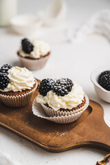 muffin cupcake paper mold carrot cake topped with whipped cream and berries 
blackberry