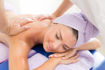 Obraz na płótnie Canvas Young smiling woman getting back massage in massage salon
