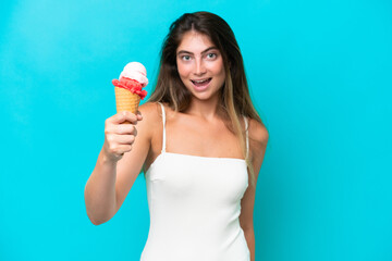 Young woman in swimsuit holding an ice cream isolated on blue background with happy expression