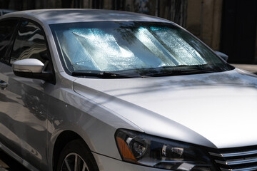 Closeup of protective reflective surface under the windshield of the passenger car parked on a hot...