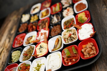 Turkish and Greek appetizers (meze) table. Traditional Turkish cuisine cold appetizers. Different types of appetizers in colorful special plates. Olives, hummus, yogurt, pickles, etc. Selective focus