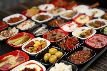 Turkish and Greek appetizers (meze) table. Traditional Turkish cuisine cold appetizers. Different types of appetizers in colorful special plates. Olives, hummus, yogurt, pickles, etc.Selective focus.