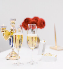 Glasses with champagne on the table. Holidays concept. Party in a large bright hall. Secular reception. Buffet at a secular party. Lots of wine glasses. Gala dinner or event. Vertical photo.