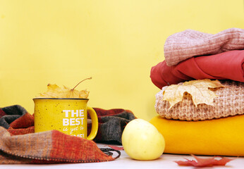 Autumn. Clothes warm mug and apple on a yellow background