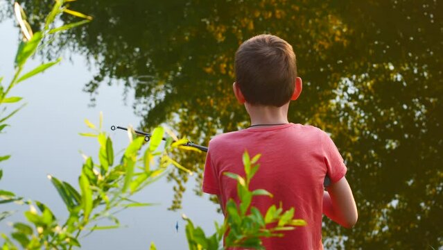 a boy of 8 years old is fishing on a pond with a fishing rod on a summer day.the child's summer vacation on a fishing trip. hobby fishing for a child. fishing with a fishing rod