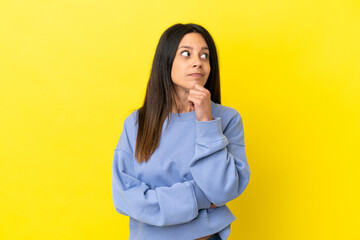 Young caucasian woman isolated on yellow background having doubts and thinking