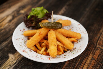 Potato croquettes with french fries on the white plate. Delicious unhealthy appetizer. Beer platter on wooden background with pickles. Snack for beer or drink.