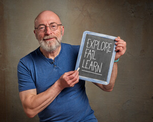 explore, fail and learn - inspirational note, white chalk writing on a slate blackboard held by a...