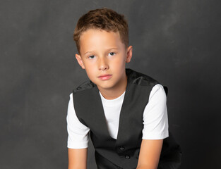 Handsome boy in black vest and white shirt isolated on gray background - 521885242