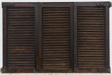 Fototapeta na wymiar Closed brown wooden shutters on a white wall