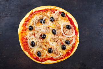 Traditional Italian pizza al tonno with tuna, onion and olives served as top view on an old rustic...