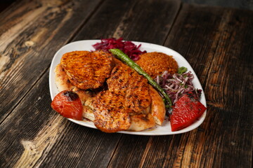 Grilled chicken breast. Fried chicken fillet with onions, bulgur, roasted green pepper, and roasted tomato on a white plate. Delicious Grilled chicken breast.