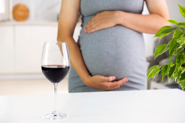 Future mother and glass of wine. Pregnancy and bad habits. Prenatal care and alcohol abuse.