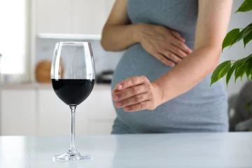 Foto op Plexiglas Pregnant woman stretch hand to glass of wine and want to have a drink. Pregnancy and bad habits. Prenatal care and alcohol abuse. © Татьяна Немировская