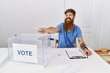 Young redhead politic party worker smiling happy holding vote at electoral college.