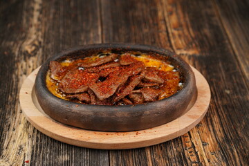 Delicious Fried eggs with pastrami inside in a casserole on wooden background. Fried eggs with pastrami made with butter.