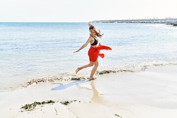 Young cuacasian girl smiling happy dancing at the beach.