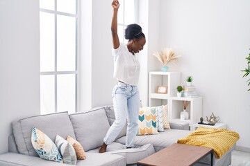 African american woman smiling confident dancing on sofa at home