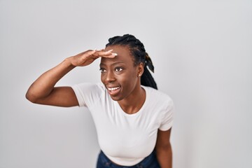 Beautiful black woman standing over isolated background very happy and smiling looking far away...