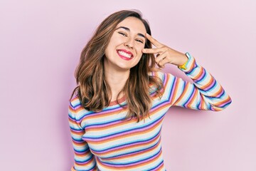 Young hispanic girl wearing casual clothes doing peace symbol with fingers over face, smiling...