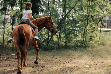 A girl rides a horse in the hot summer in the forest
