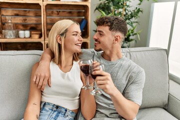 Young caucasian couple smiling happy toasting with red wine at home.