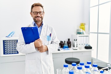 Middle age hispanic man smiling confident wearing scientist uniform at laboratory