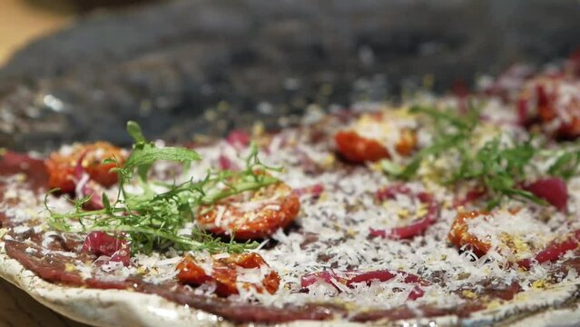 Chef putting ruccula on carpaccio dish of thinly sliced pieces of raw beef tenderloin