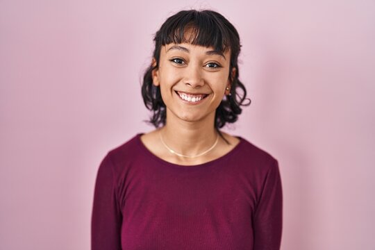 Young beautiful woman standing over pink background with a happy and cool smile on face. lucky person.