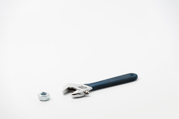 chrome adjustable wrench and unscrewed nut on a white background