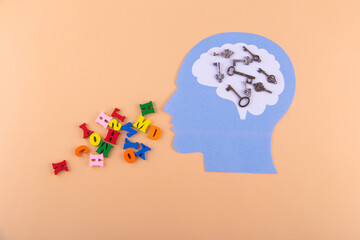 Man head silhouette with various keys in head area and letters running out mouth on light pink...