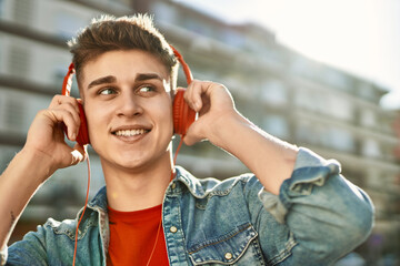 Young caucasian guy wearing headphones listening to music at the city
