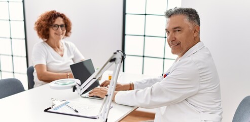 Obraz premium Middle age man and woman wearing doctor uniform having medical consultation at clinic