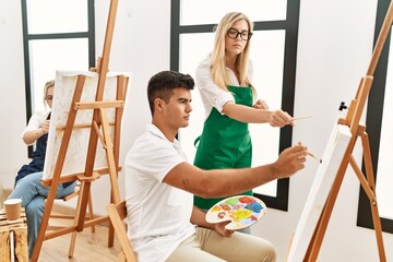 Art woman teacher with serious expression looking draw of paint student at studio.