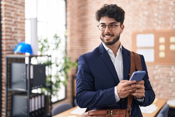 Young hispanic man business worker using smartphone at office