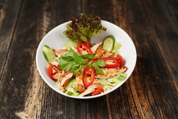 Salad with fried chicken. Salad made with fried chicken, tomatoes, cucumber, green pepper, and grated cheese in a white bowl. Delicious health food.