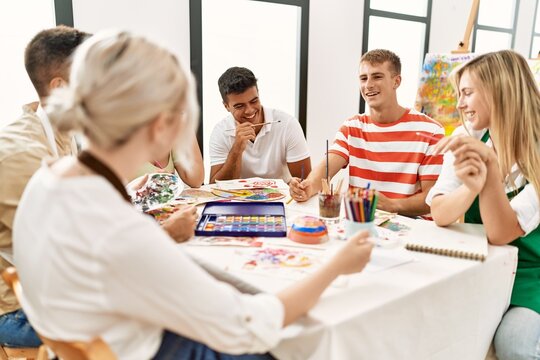 Group of people smiling happy drawing sitting on the table at art studio.
