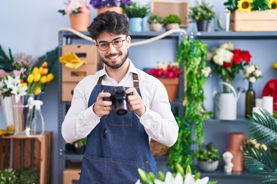 Young hispanic man florist make photo to flowers at florist shop