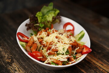Salad with fried chicken. Salad made with fried chicken, tomatoes, cucumber, green pepper, and grated cheese in a white bowl. Delicious health food.